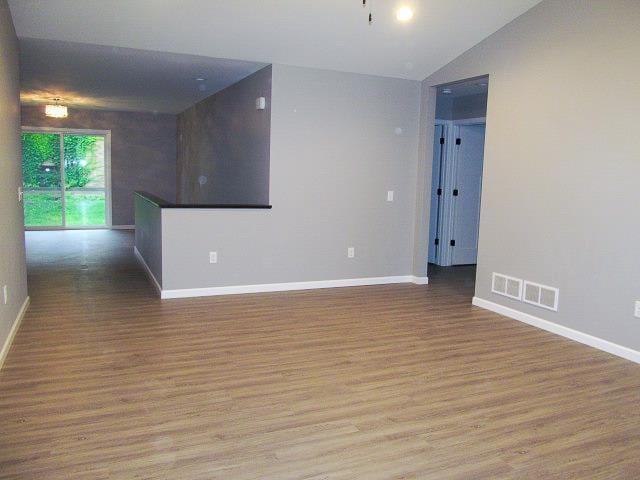 unfurnished room with vaulted ceiling and light wood-type flooring