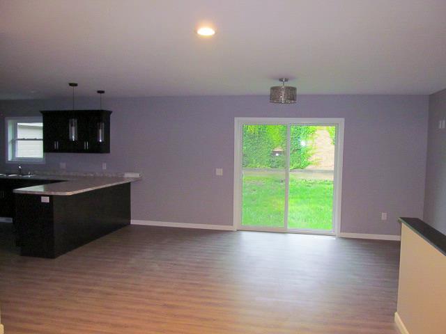 kitchen featuring kitchen peninsula, light hardwood / wood-style flooring, hanging light fixtures, and sink