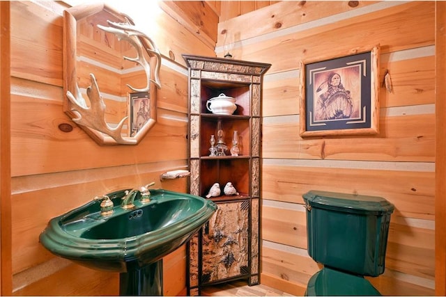 bathroom featuring wooden walls and toilet