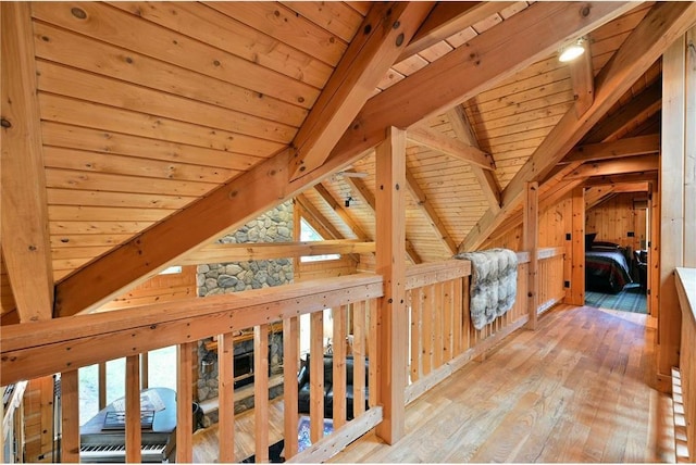 corridor with vaulted ceiling with beams, light hardwood / wood-style floors, wooden ceiling, and wood walls