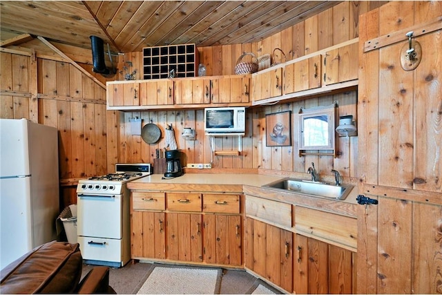 kitchen featuring white appliances, wooden ceiling, sink, wooden walls, and vaulted ceiling