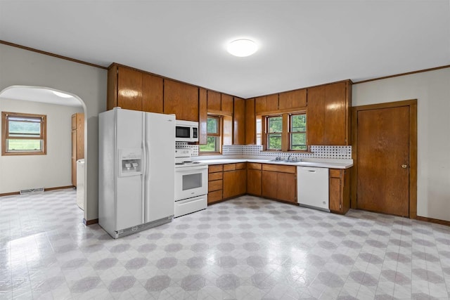 kitchen with decorative backsplash, crown molding, and white appliances