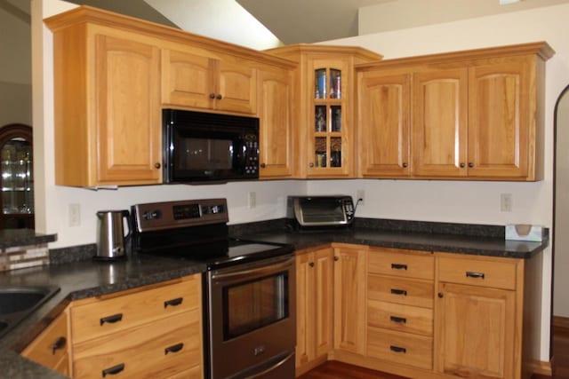 kitchen featuring stainless steel electric range, vaulted ceiling, dark stone countertops, and wood-type flooring