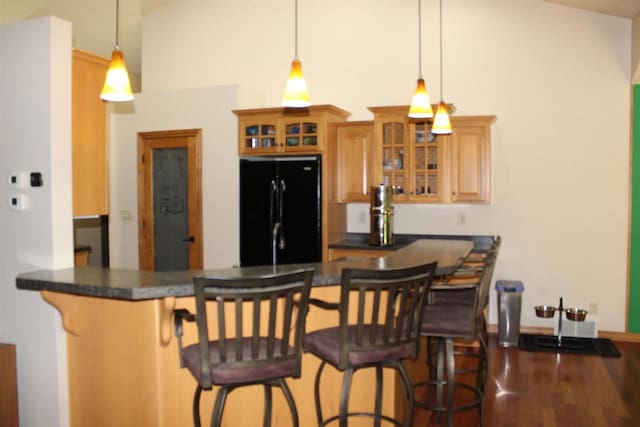 kitchen with a kitchen bar, black refrigerator, pendant lighting, and kitchen peninsula