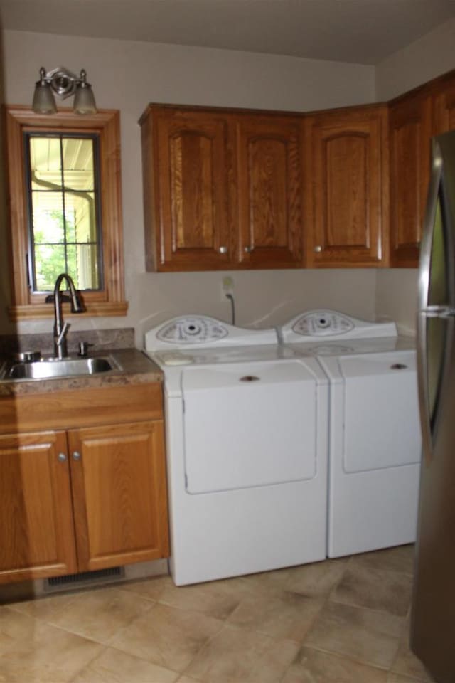 clothes washing area featuring cabinets, sink, washer and clothes dryer, and light tile patterned flooring