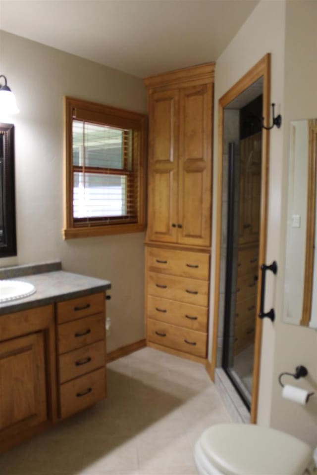 bathroom with toilet, vanity, an enclosed shower, and tile patterned flooring