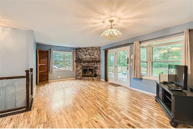 living room with a fireplace, light wood-type flooring, and an inviting chandelier