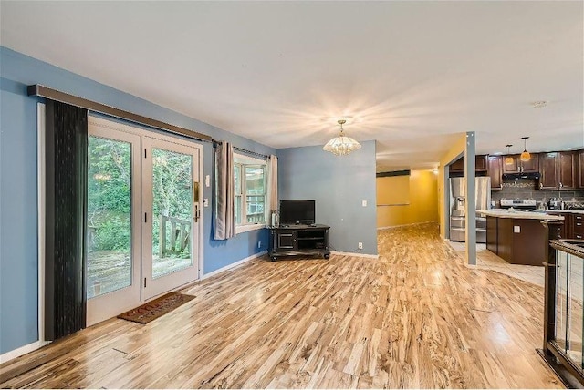 unfurnished living room with light hardwood / wood-style flooring and an inviting chandelier