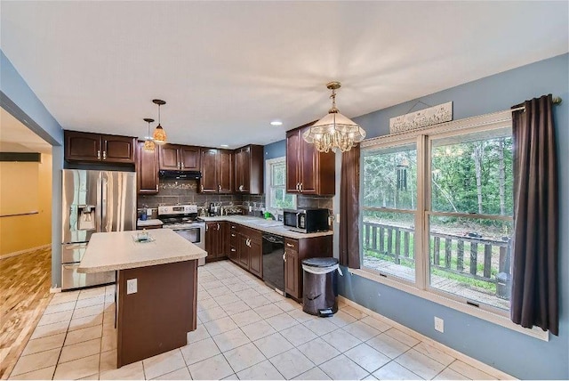 kitchen featuring appliances with stainless steel finishes, dark brown cabinetry, a kitchen island, hanging light fixtures, and light tile patterned flooring