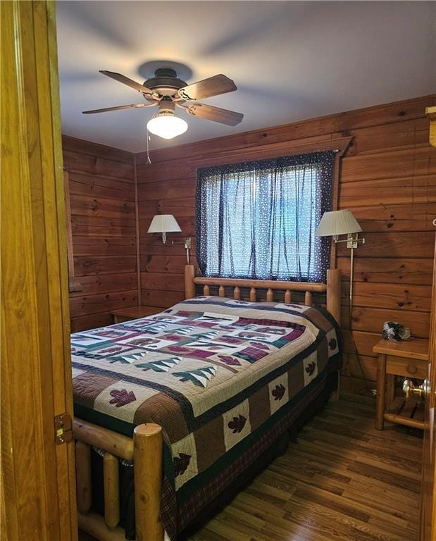 bedroom featuring ceiling fan, dark hardwood / wood-style floors, and wood walls