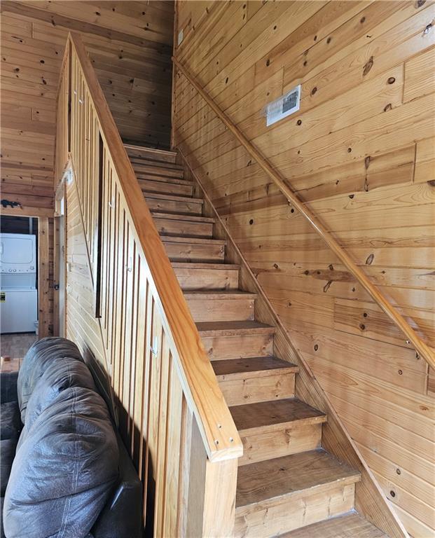 stairway with a towering ceiling, wooden ceiling, and wooden walls