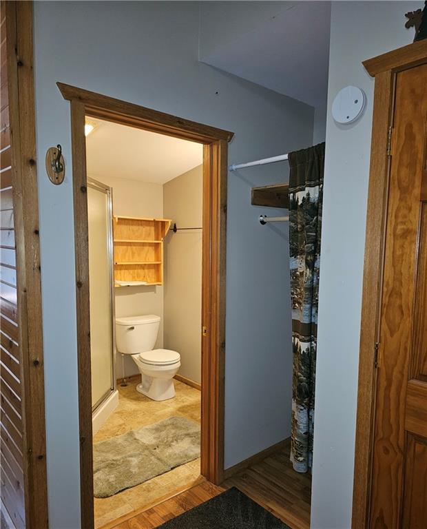 bathroom with hardwood / wood-style floors, toilet, and walk in shower