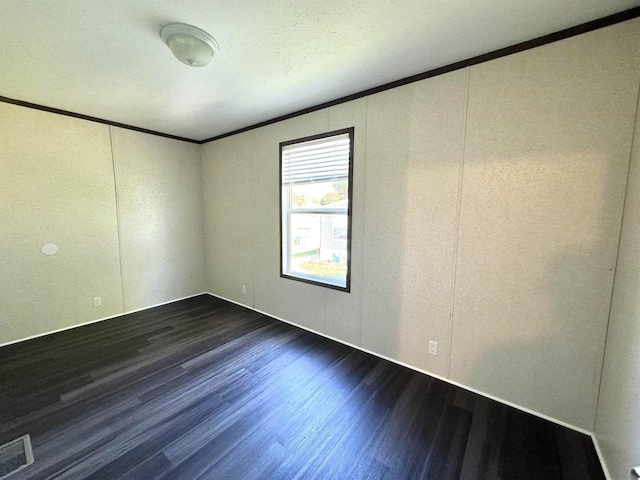 spare room with dark hardwood / wood-style flooring, ornamental molding, and a textured ceiling