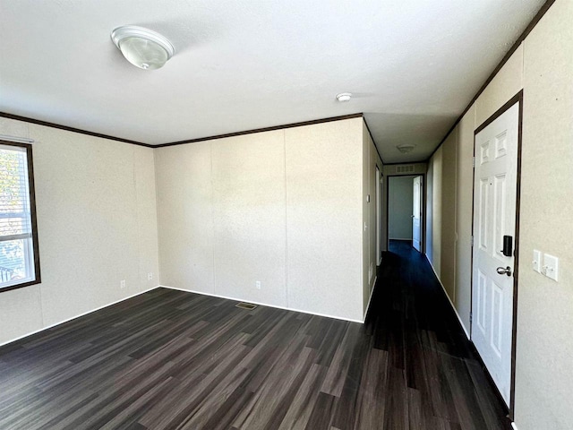 spare room featuring ornamental molding and dark wood-type flooring