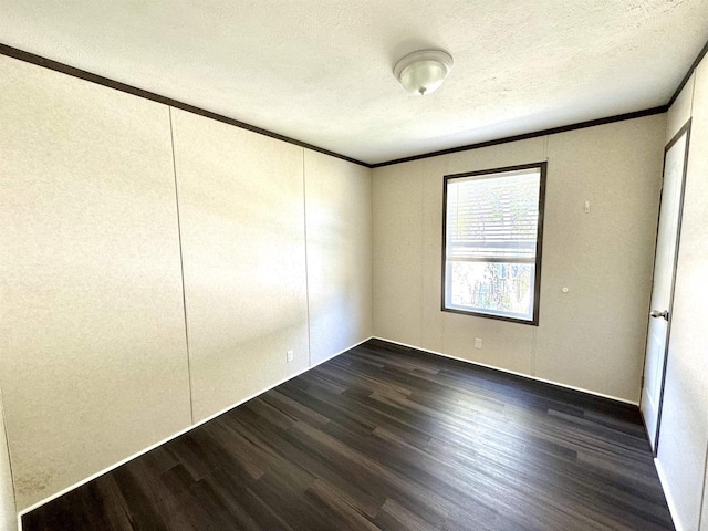 empty room with dark hardwood / wood-style floors, crown molding, and a textured ceiling