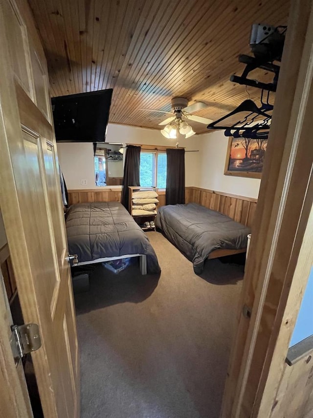 carpeted bedroom featuring ceiling fan, wooden ceiling, and wooden walls