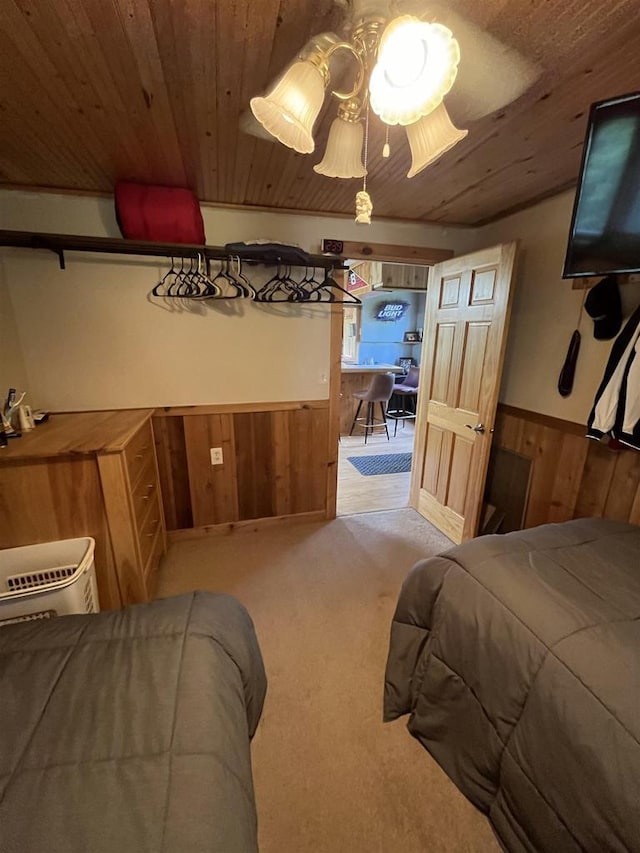 bedroom with wood ceiling, wood walls, and light colored carpet