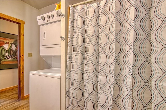 washroom with stacked washing maching and dryer and light hardwood / wood-style floors