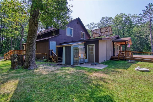 rear view of property featuring a yard and a wooden deck