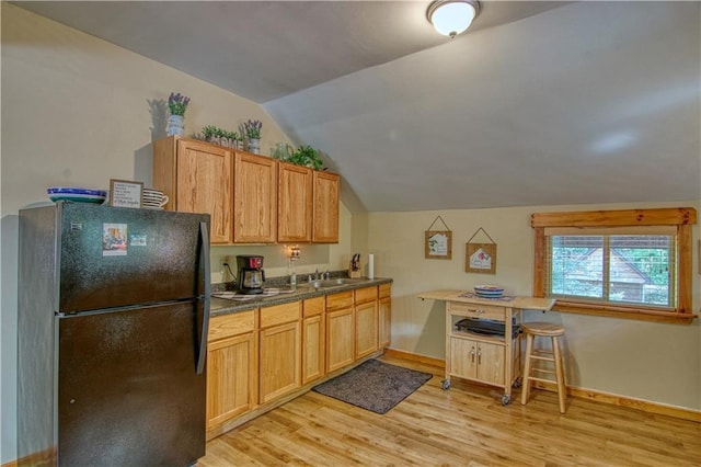 kitchen with light hardwood / wood-style flooring, black fridge, lofted ceiling, and sink