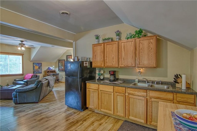 kitchen with lofted ceiling, black refrigerator, sink, ceiling fan, and light wood-type flooring