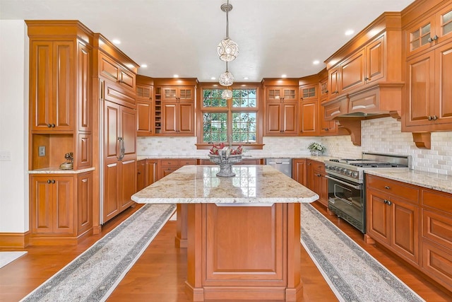 kitchen featuring light stone countertops, a center island, dark wood-type flooring, hanging light fixtures, and high end appliances