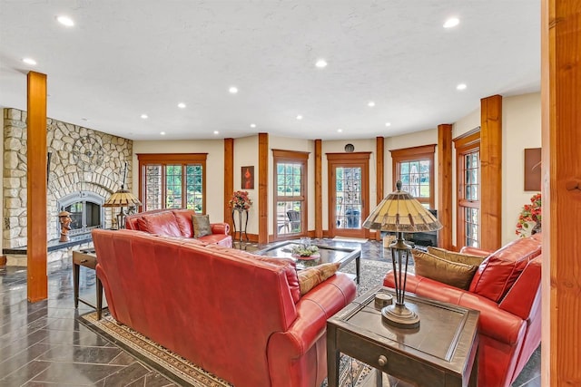 living room with plenty of natural light and a stone fireplace