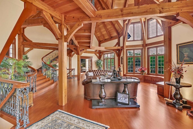 living room featuring beamed ceiling, wooden ceiling, hardwood / wood-style floors, and a high ceiling