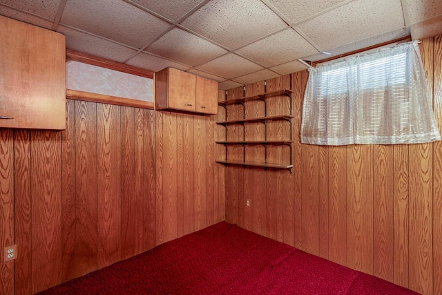 interior space with a paneled ceiling and wood walls