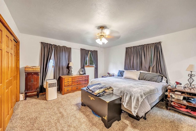 bedroom featuring a closet, a textured ceiling, light colored carpet, and ceiling fan