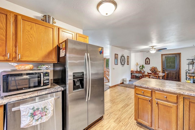 kitchen with a textured ceiling, stainless steel appliances, light hardwood / wood-style flooring, and ceiling fan