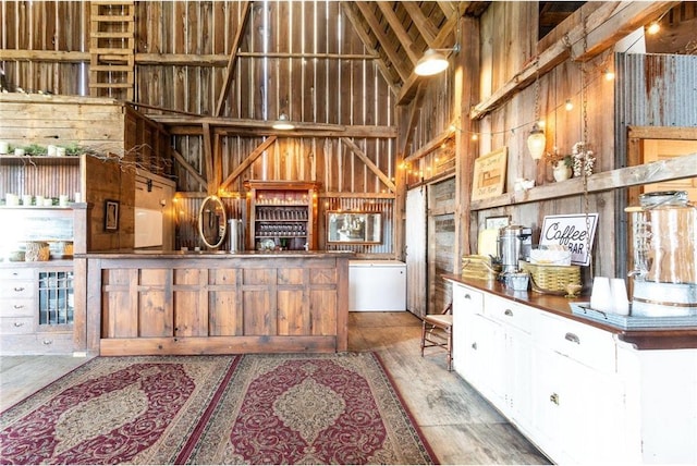 kitchen with high vaulted ceiling, hardwood / wood-style floors, and wooden walls