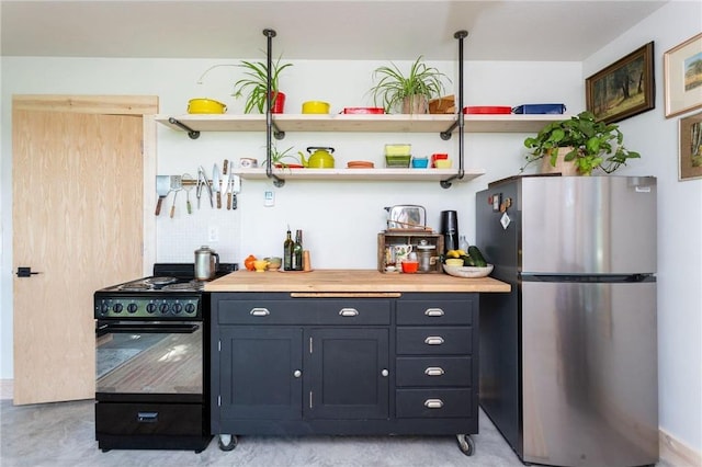 kitchen featuring black stove, wood counters, and stainless steel refrigerator