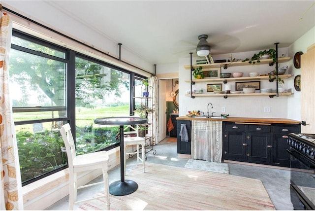 interior space featuring ceiling fan, sink, decorative backsplash, and black range with gas stovetop