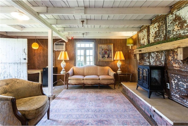 living room with a wall mounted AC, a wood stove, wood walls, and beamed ceiling