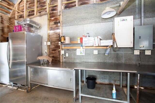 kitchen featuring stainless steel refrigerator, concrete floors, and electric panel