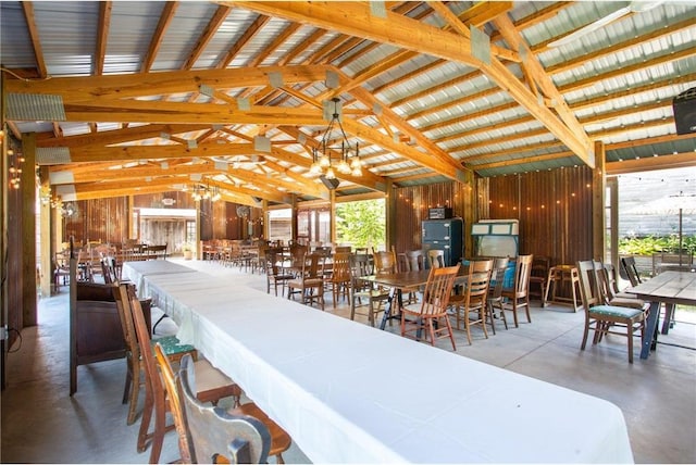 dining room featuring high vaulted ceiling, beam ceiling, wood walls, and concrete floors