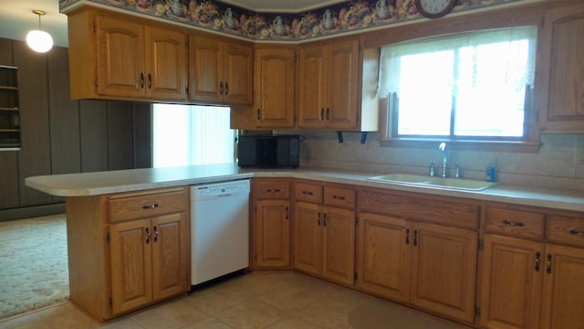 kitchen with kitchen peninsula, pendant lighting, light tile patterned floors, white dishwasher, and sink