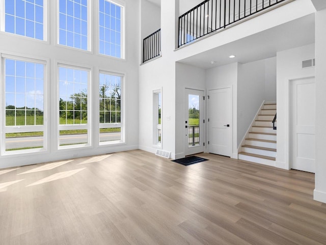 entryway featuring a towering ceiling and light hardwood / wood-style flooring