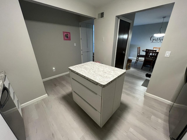 kitchen featuring white cabinets, hanging light fixtures, light hardwood / wood-style flooring, and a center island