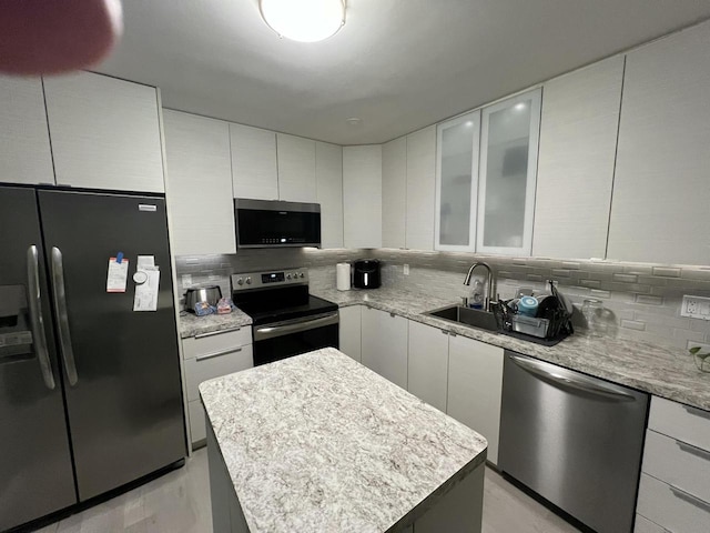 kitchen with sink, stainless steel appliances, white cabinetry, and a center island