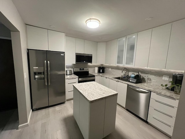 kitchen featuring stainless steel appliances, white cabinets, a center island, and light hardwood / wood-style flooring