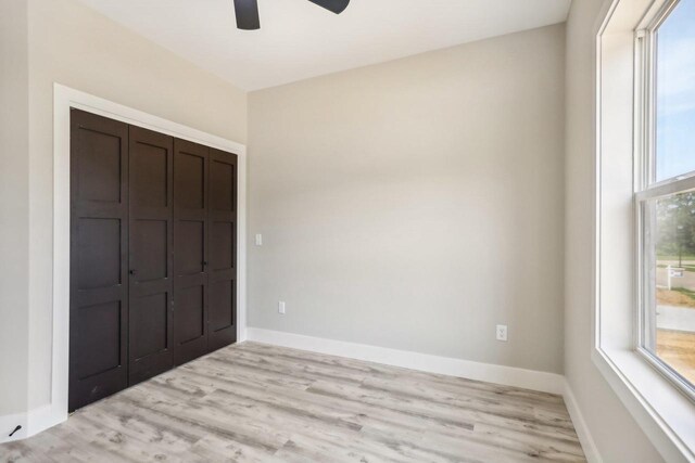 unfurnished bedroom with a closet, light wood-type flooring, and ceiling fan