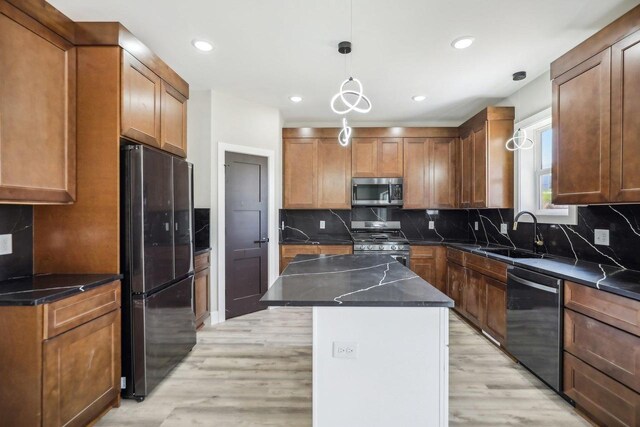 kitchen featuring pendant lighting, light wood-type flooring, sink, a kitchen island, and appliances with stainless steel finishes