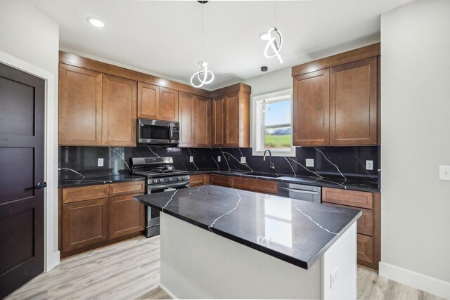 kitchen featuring appliances with stainless steel finishes, light hardwood / wood-style flooring, decorative backsplash, and a kitchen island