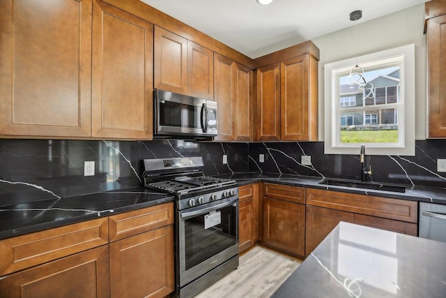 kitchen with sink, decorative backsplash, light wood-type flooring, and stainless steel appliances