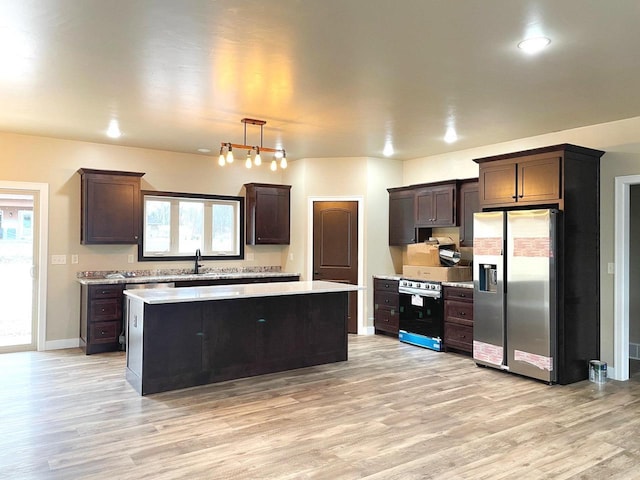 kitchen with light hardwood / wood-style floors, appliances with stainless steel finishes, a kitchen island, pendant lighting, and sink