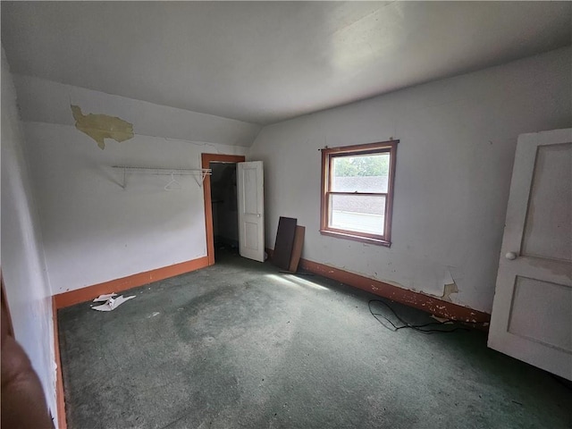 carpeted empty room with lofted ceiling