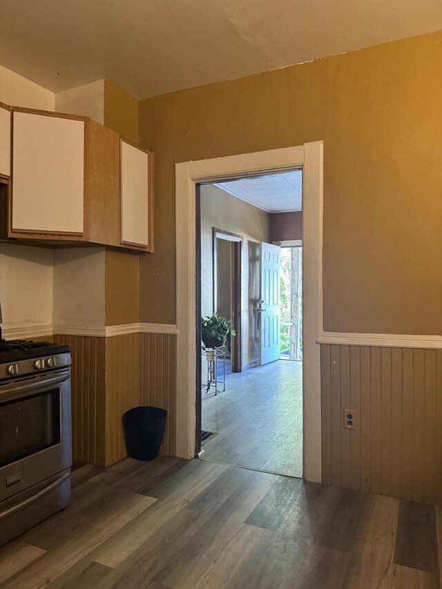 kitchen with wood-type flooring, gas range, and wood walls