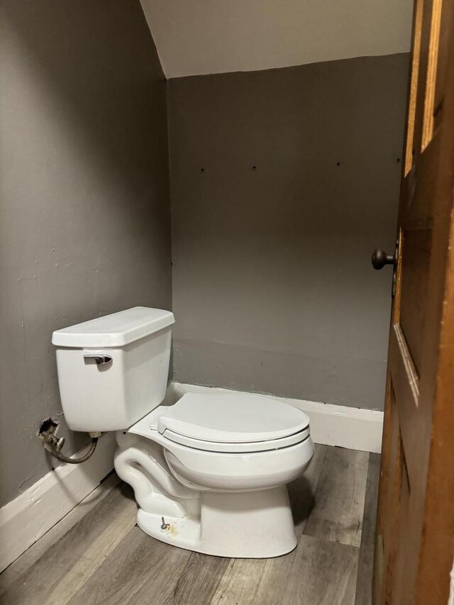 bathroom featuring toilet, vaulted ceiling, and wood-type flooring